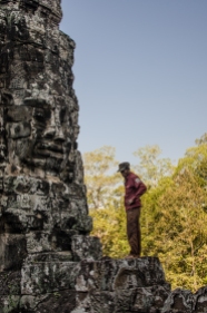 un homme devant un statut sur le site d'Angkor en Cambodge