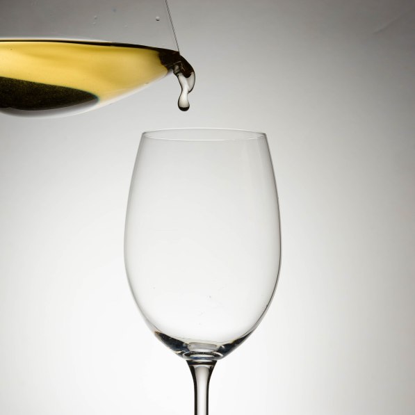 product photography pouring white wine into an empty glass